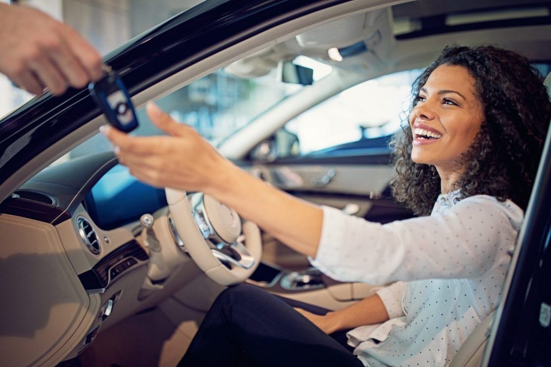 Car dealer giving a key for a new car to a woman