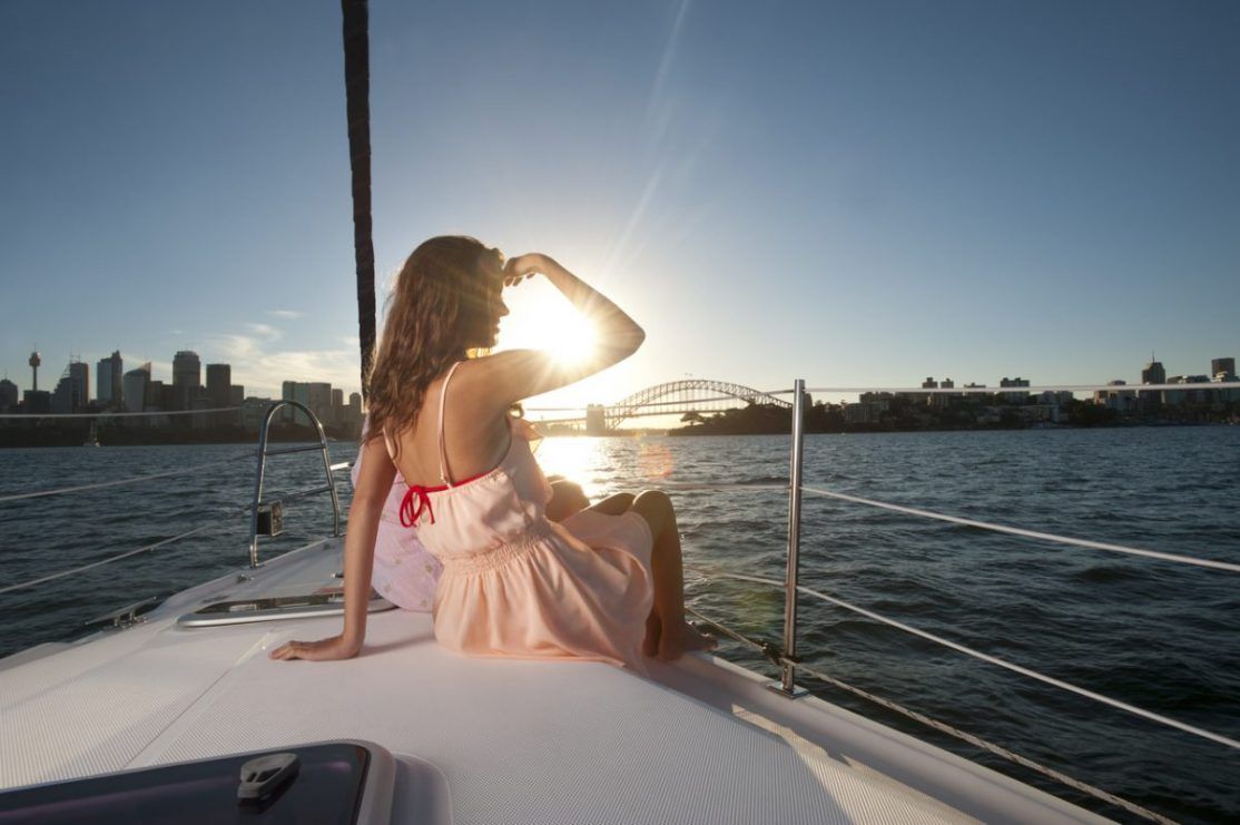 Woman looking out to sea at the view of the Sydney Harbour Bridge at sunset.