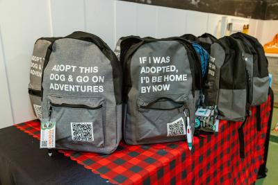 Multiple adventure buddy program backpacks with writing on them noting the dog is adoptable