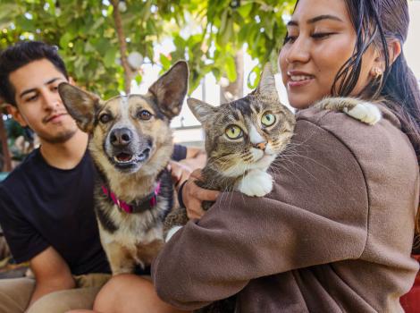 Two people, one holding a cat and one holding a dog
