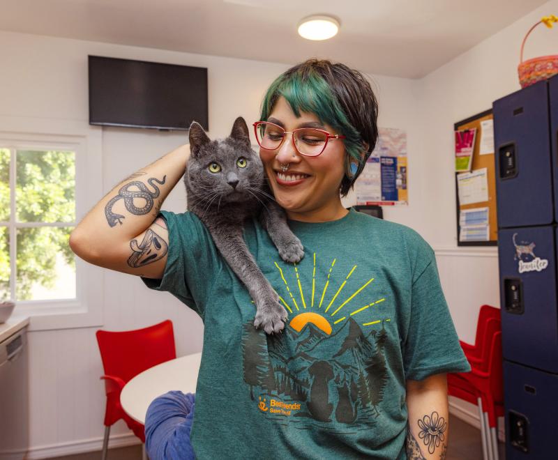 Smiling person looking at an adoptable cat sitting on their shoulder