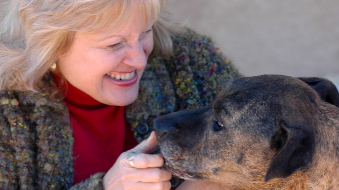 Ledy VanKavage smiling and interacting with a dog