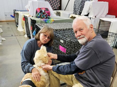 Volunteers Rich and Linda Yates with a dog beside some crates