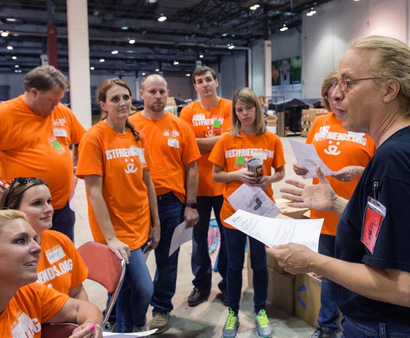 Person holding a clipboard talking to a group of people listening