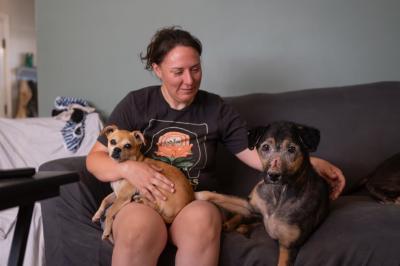 Debbi Carman with David Bowie the dog on a couch with another small dog in her lap