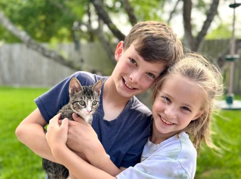 Two children holding Sarah the kitten