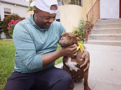 Smiling person sitting with a dog outside on some steps